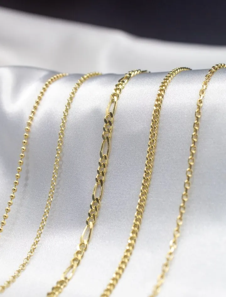 Variety of 18k Gold chains on white fabric